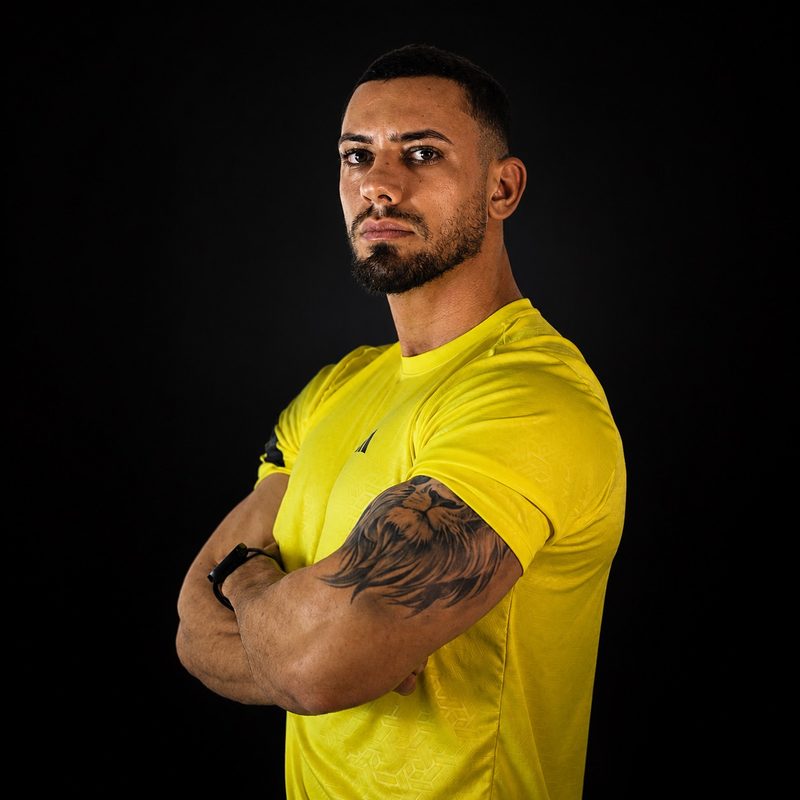 Luiz Severo, personal trainer, de camisa amarela e braços cruzados